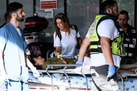 TEL AVIV, ISRAEL - 2023/10/07: A woman holds the hand of a wounded soldier arriving at the emergency entrance to the Ichilov hospital in Tel Aviv following a Hamas incursion into Israeli settlements around the Gaza strip. (Matan Golan, SOPA Images, LightRocket via Getty Images)