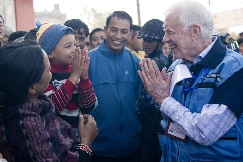 Former President Carter greets a boy during 2013 elections in Nepal. The Carter Center has safeguarded 115 democratic elections in 40 countries.