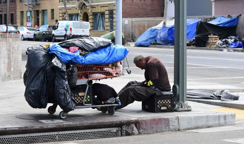 A homeless man sits next to his belongings on the streets of the Skid Row community of Los Angeles, California, April 26, 2021. -- A federal judge overseeing a trial that aims to end the homelessness crisis in Skid Row in the city is not backing down from its ordinance requiring all indigent people in the area to be offered shelter within six months. U.S. District Judge David O. Carter is opening the door to further discussions by setting additional court dates and clarifying parts of his ruling. (Frederic J. Brown, AFP, Getty Images)