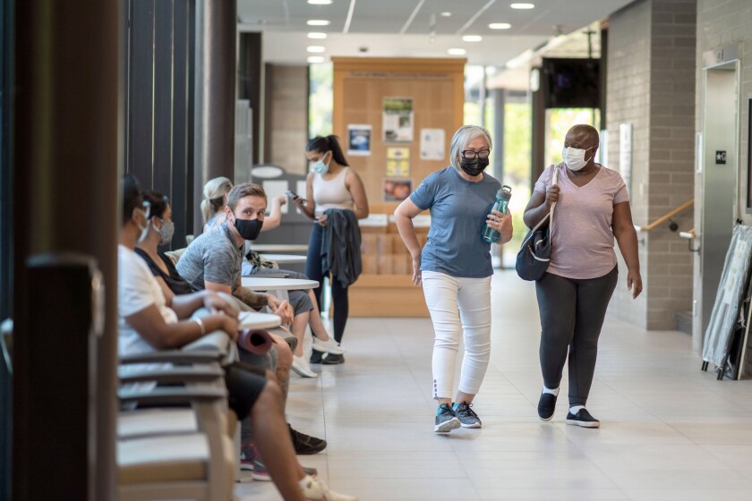 Two women walk through the annex of a community center gym and greet the people they see. (FatCamera, Getty Images)