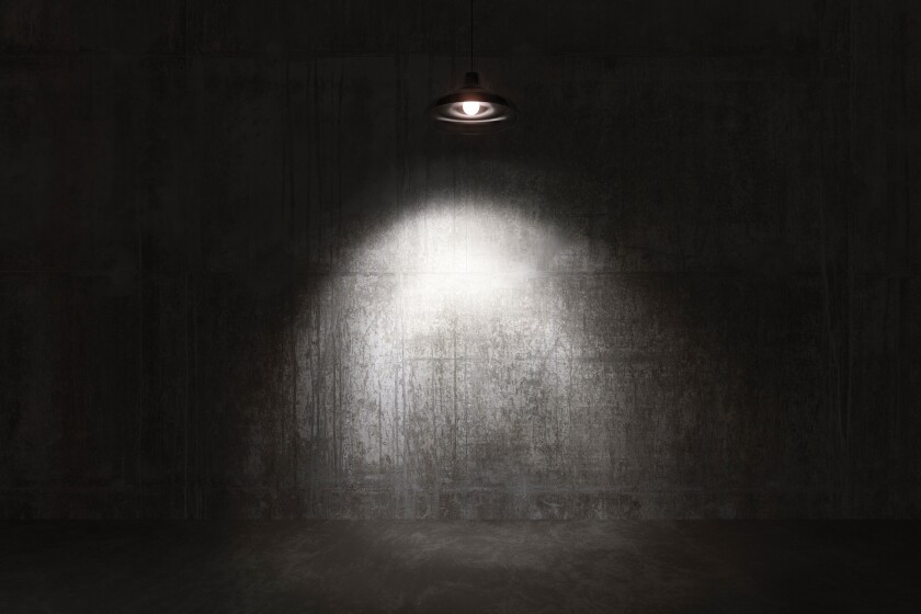 A spotlight on a bare concrete wall in an interrogation room