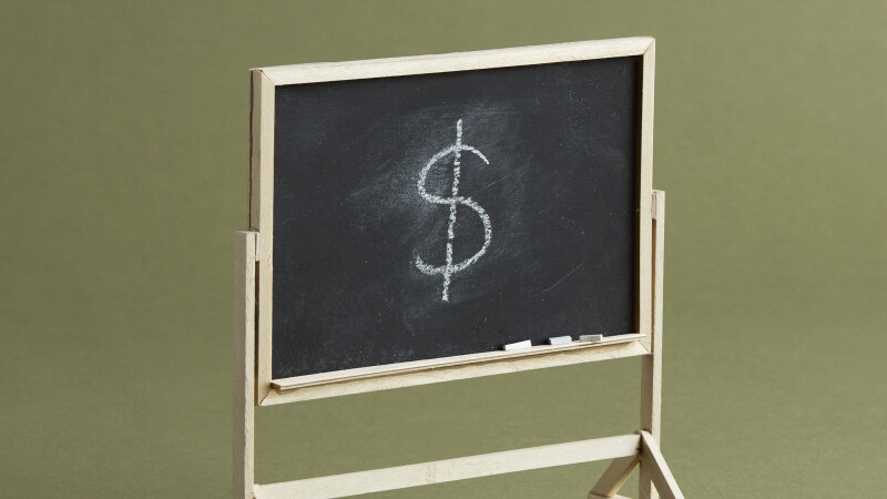 Photo illustration of a classroom blackboard with a dollar sign drawn in chalk