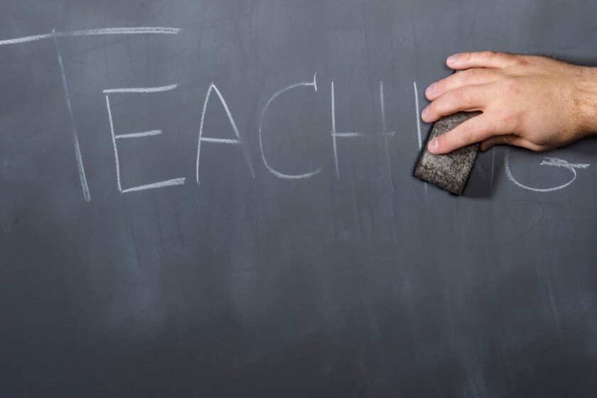 hand erasing the word teaching on a chalkboard