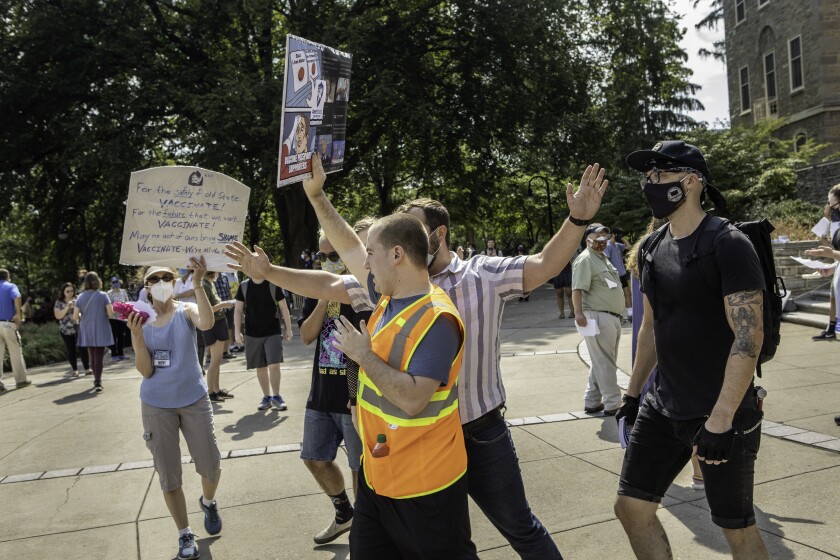 Baker (in striped shirt), an assistant professor of English and African American studies, blocks Rachlin (in neon vest), a student and anti-vax protester, from vaccine supporters.