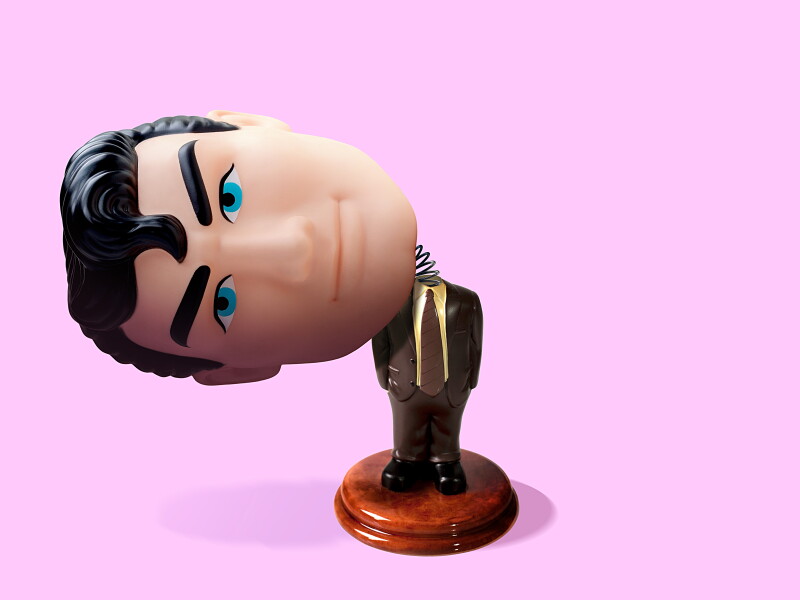Photo-based illustration of a bobblehead-type figurine with a larger head that has sprung loose and tilted to the side.