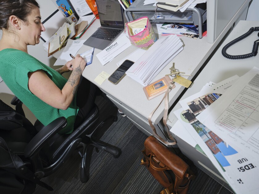 Liz Franczyk, an adjunct professor at MATC, and administrator of the FASTFund writes checks for recipients of the FASTFund in her office on the MATC Downtown Campus in Milwaukee, Wisconsin.
